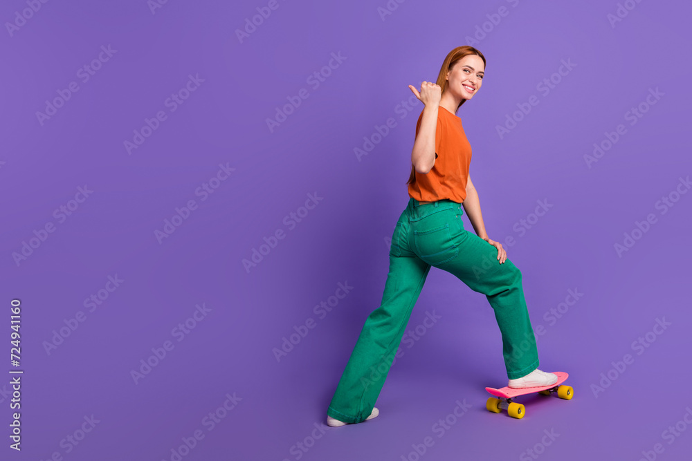 Full body length photo of attractive woman spend free time riding penny board point finger mockup isolated on purple color background