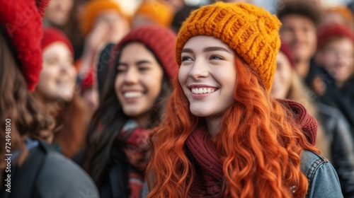 Close-up portrait of a smiling young woman with curly red hair wearing an orange beanie