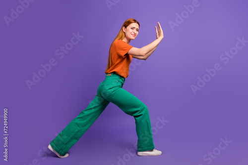 Full length body photo of young woman solving all problems and difficulties alone pushing empty space isolated on violet color background