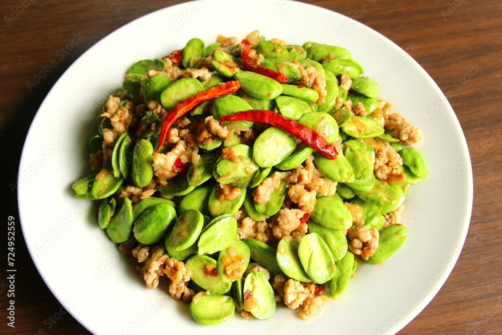 Stir fried stink beans with minced pork dried red chili peppers on top. close up photo top view on wooden background Stir fried stink beans with minced pork dried red chili peppers on top. close up photo top view on wooden background