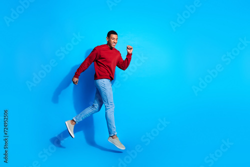 Full length profile portrait of nice satisfied person jump run empty space ad isolated on blue color background