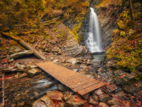 view to waterfall in canyon and wooden bridge on foreground