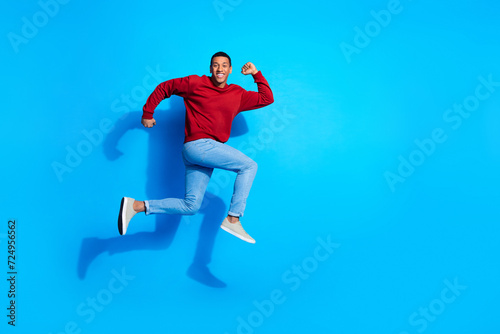 Full length profile portrait of handsome man jump rush empty space ad isolated on blue color background