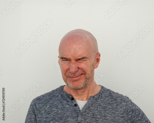 portrait of a bald man squinting into the sun