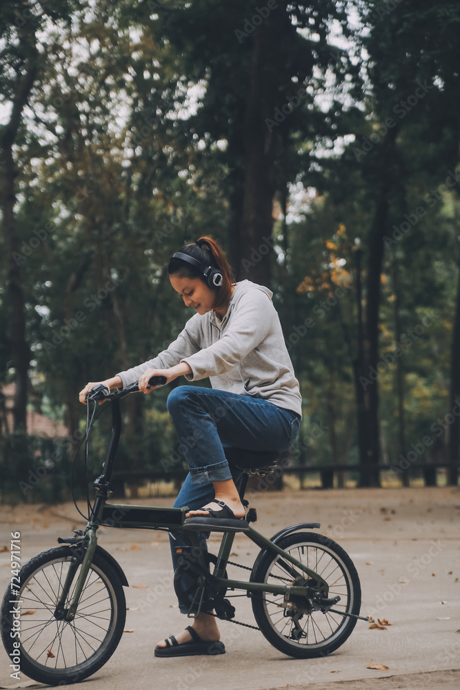 Fototapeta premium Happy Asian young woman walk and ride bicycle in park, street city her smiling using bike of transportation, ECO friendly, People lifestyle concept.