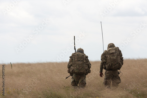 Dos soldados armados de Estados Unidos con uniforme  durante unos ejercicios militares caminan por el campo. photo