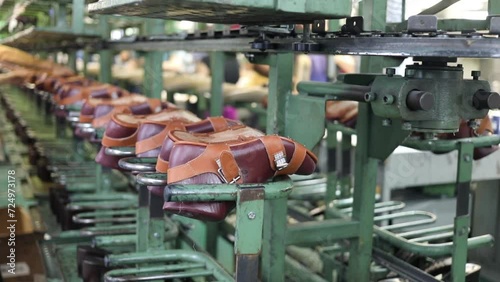 Shoes move on conveyor in shoes factory, people out of focus, slow motion photo