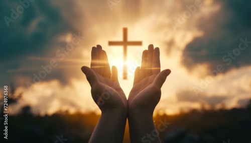 Silhouette of hands presenting Christian cross against sunset photo