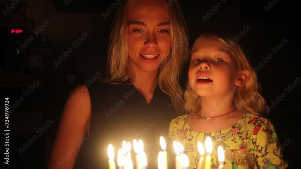 Little girl and her mother blow candles on cake at birthday, slow motion