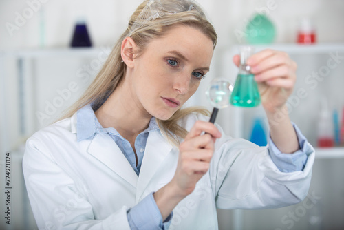 woman holding magnifying glass for analysis test tubes