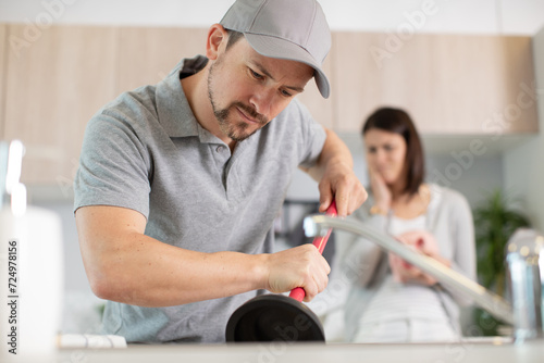 close-up of a plumber using plunger in sink