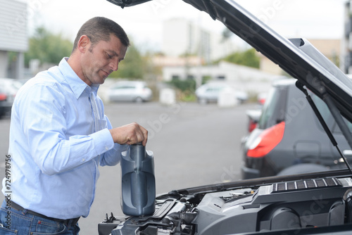 man adding fluid for cleaning in his car
