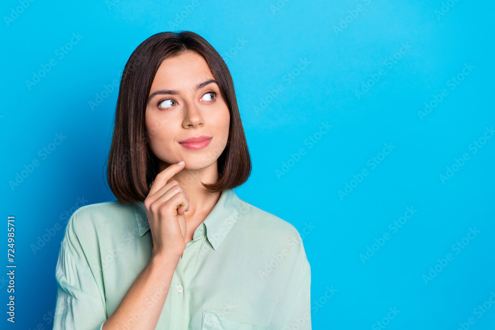 Portrait of smart cute girl with stylish hairdo wear teal shirt finger on chin look at logo empty space isolated on blue color background Portrait of smart cute girl with stylish hairdo wear teal shirt finger on chin look at logo empty space isolated on blue color background