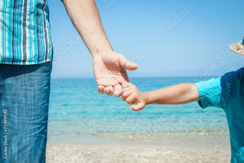 A hands of a happy parent and child by the sea in nature travel