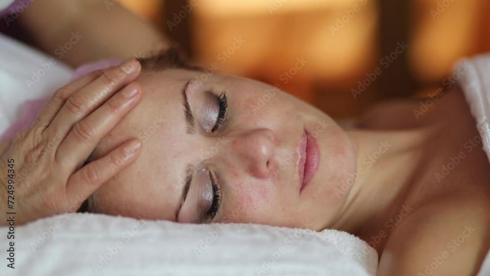 Massage therapist does thai massage of head for woman in spa room, slow motion
