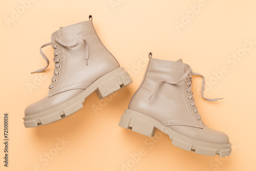 Beige trendy boots on color background, top view.