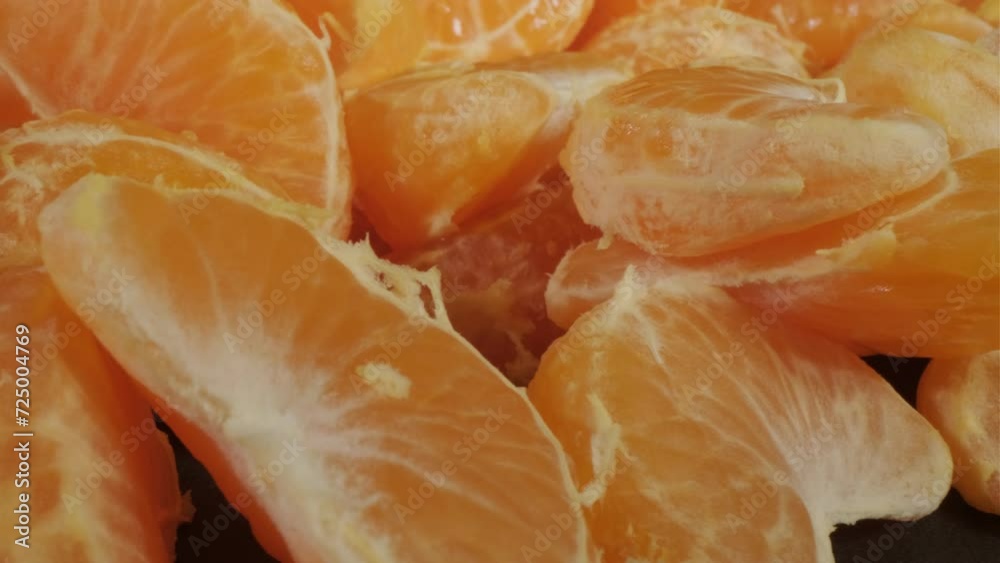 Peeled tangerines on a black background. Slices of tangerine or mandarin fruit close up Peeled tangerines on a black background. Slices of tangerine or mandarin fruit close up