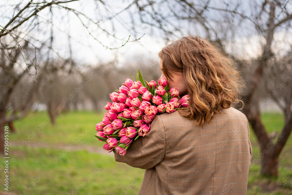 Blonde girl in beige jacket with a large bouquet of pink tulips Blonde girl in beige jacket with a large bouquet of pink tulips