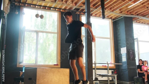 Young man performs box jump exercise increasing lower body part in gym. Athlete improves physical endurance with plyometric exercise photo
