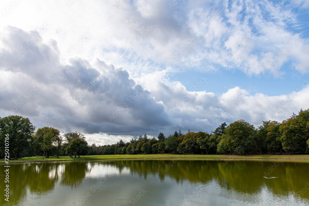Panoramic view over a pond with tree line and dramatic clouded sky in National Park Hoge Veluwe, Hoenderloo the Netherlands