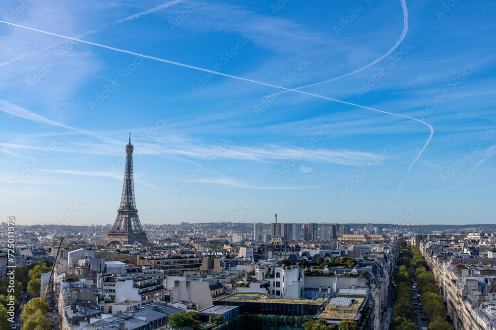 Panoramic high level view over Paris, France in southernly direction with as most distinct landmark the Eiffel Tower on a clear day with condensation trails or contrails of various planes in the sky