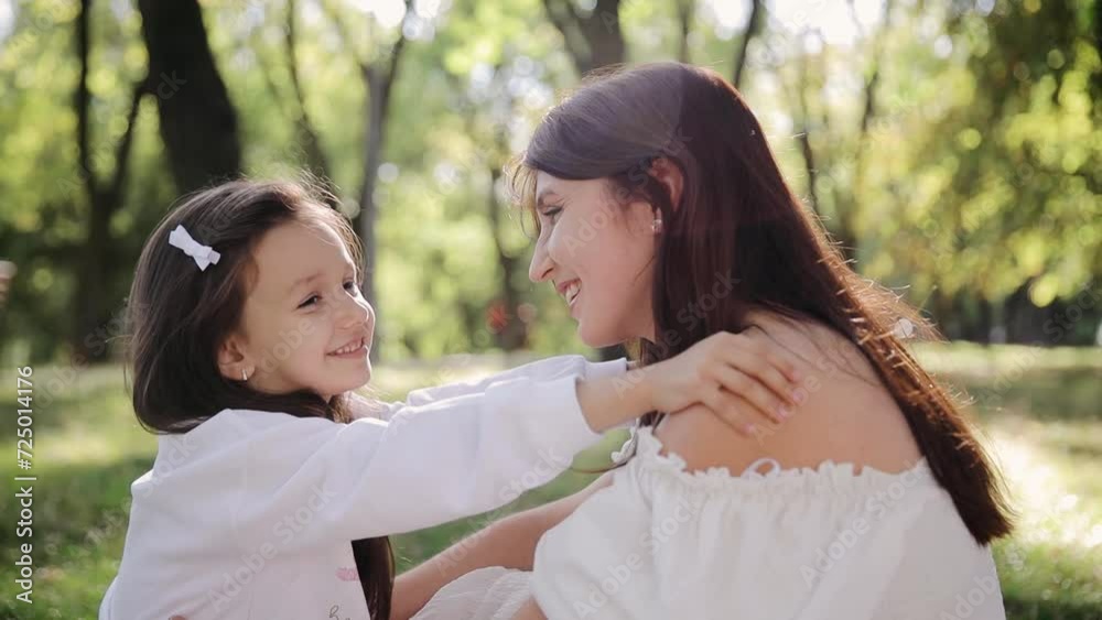 The daughter hugs her mother, gently touching her shoulder. A family having a positive time during a picnic in the park The daughter hugs her mother, gently touching her shoulder. A family having a positive time during a picnic in the park