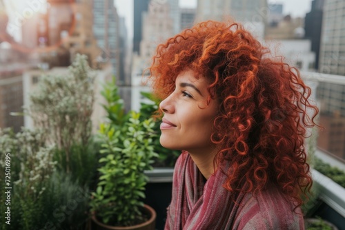Woman with ruby red curly hair enjoying a rooftop garden in the city