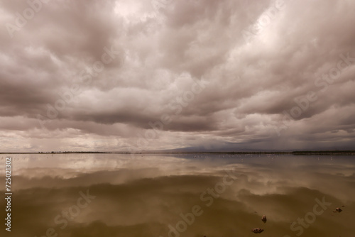 dramatic clouds are reflected in the water surface of a lake in Amboseli NP