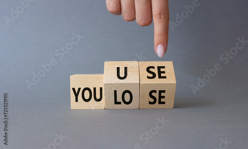 You use or lose symbol. Businessman hand points at cubes with words You lose or You use. Beautiful grey background. Business and You use or lose concept. Copy space