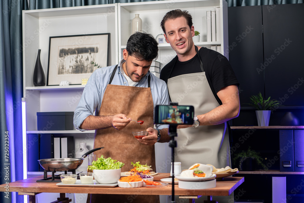 Healthy food in kitchen with chef influencers presenting fresh salad roll on cooking show streaming via smartphone on social media live, preparing ingredients vegetable soft tortilla wrap. Sellable.