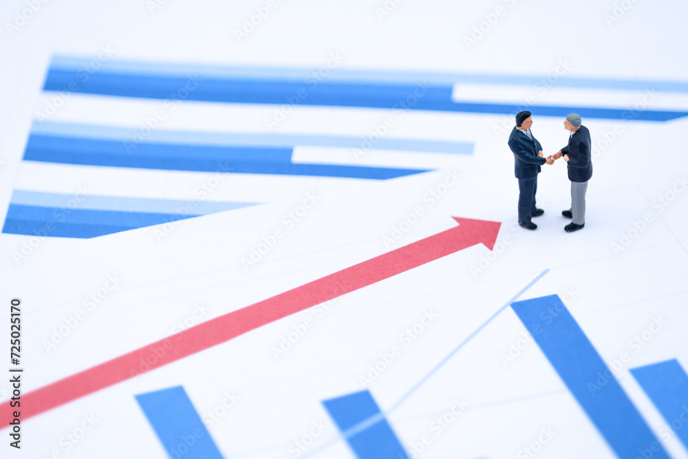 Miniature Businessmen Handshake on Growth Chart with Upward Arrows Miniature Businessmen Handshake on Growth Chart with Upward Arrows