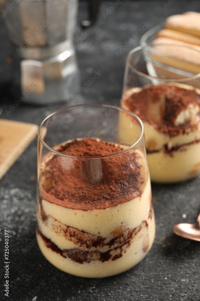Delicious tiramisu in glasses on grey textured table, closeup Delicious tiramisu in glasses on grey textured table, closeup