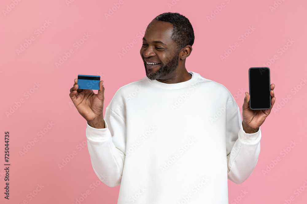 Smiling black man wearing white sweatshirt showing smart phone and credit card Smiling black man wearing white sweatshirt showing smart phone and credit card