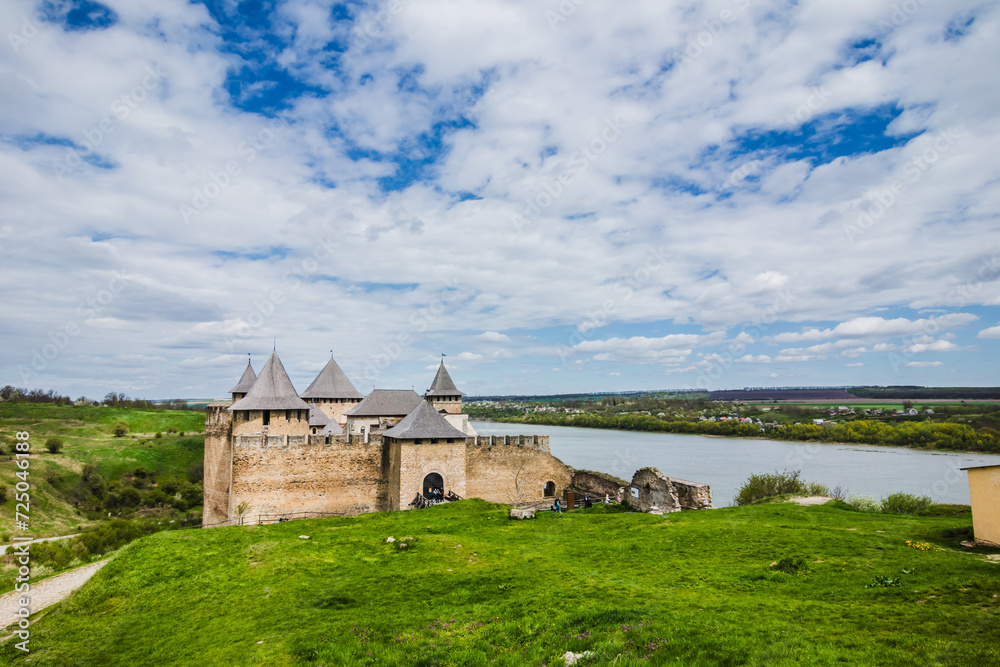 View of old castle Hotin near the river. Khotyn Fortress - medieval castle on yellow autumn hills. Ukraine, Eastern Europe. The architecture of the Middle Ages in our time.