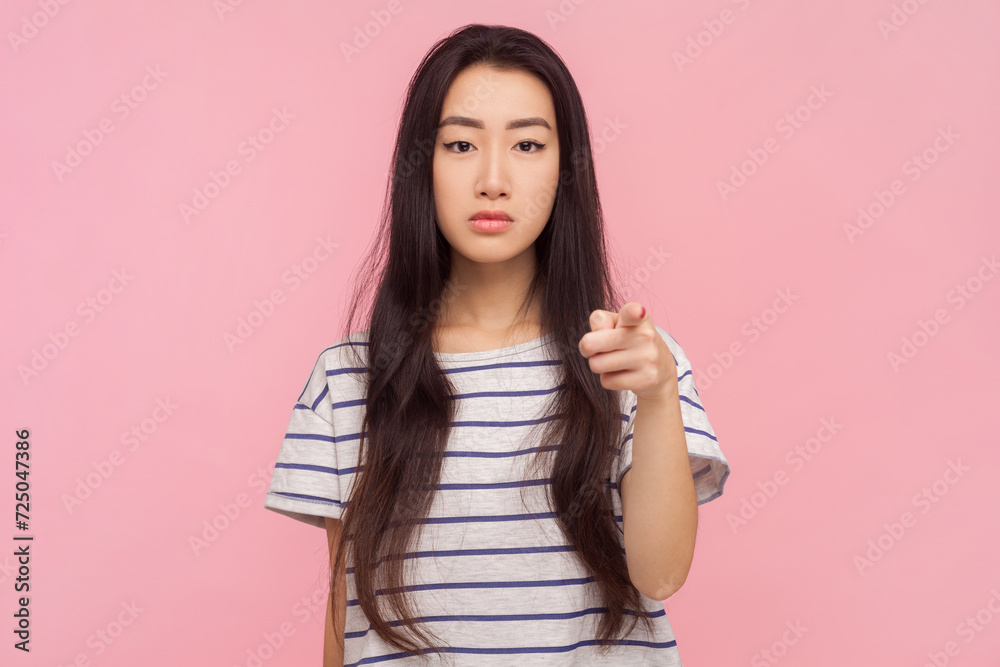 Portrait of bossy strict woman with long brunette hair pointing at camera choosing you displeased expression, wearing striped T-shirt. Indoor studio shot isolated on pink background. Portrait of bossy strict woman with long brunette hair pointing at camera choosing you displeased expression, wearing striped T-shirt. Indoor studio shot isolated on pink background.