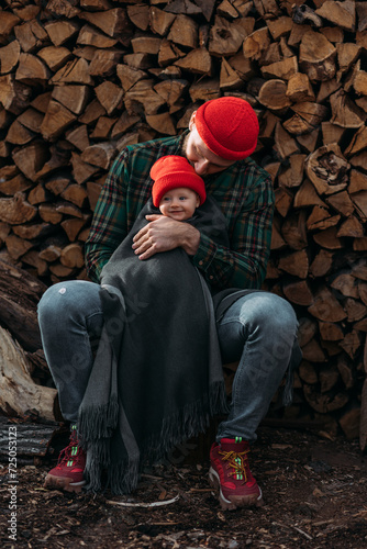 Portrait of a small child in a red hat. A small child in the arms of his father. A beautiful portrait of a child in the arms of his father. Beautiful baby photo. Family photo. Dad hugs the baby © MISHA