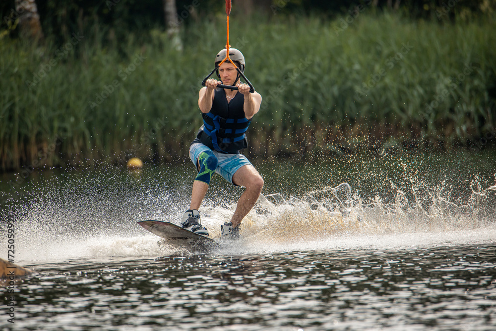 Ypung man wakeboarding and doing different board tricks. Wake boarding