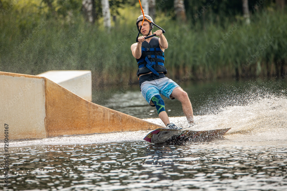 Ypung man wakeboarding and doing different board tricks. Wake boarding