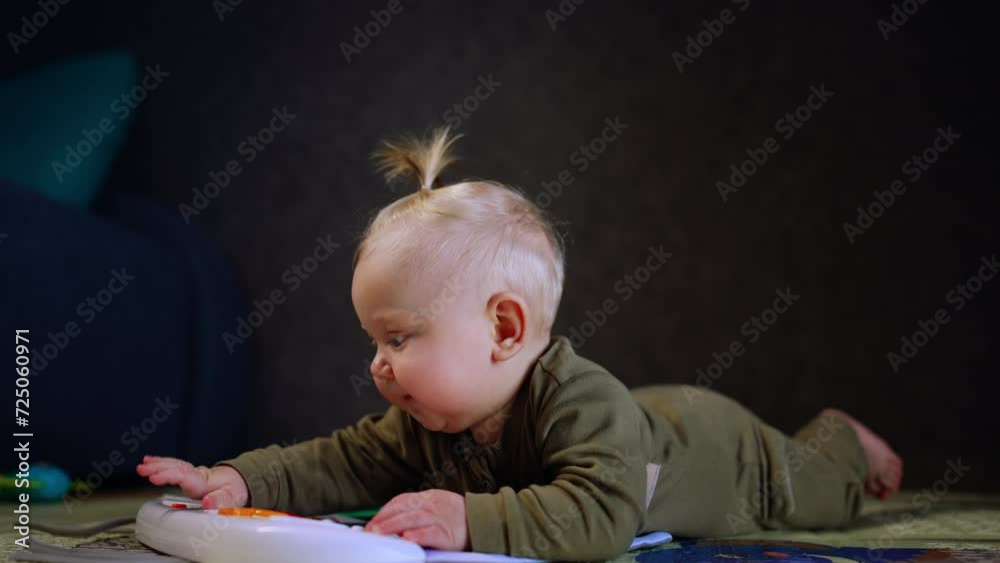 Cute smiling baby lies on the floor on his belly. Infant plays with a toy and looks up laughing. Cute smiling baby lies on the floor on his belly. Infant plays with a toy and looks up laughing.