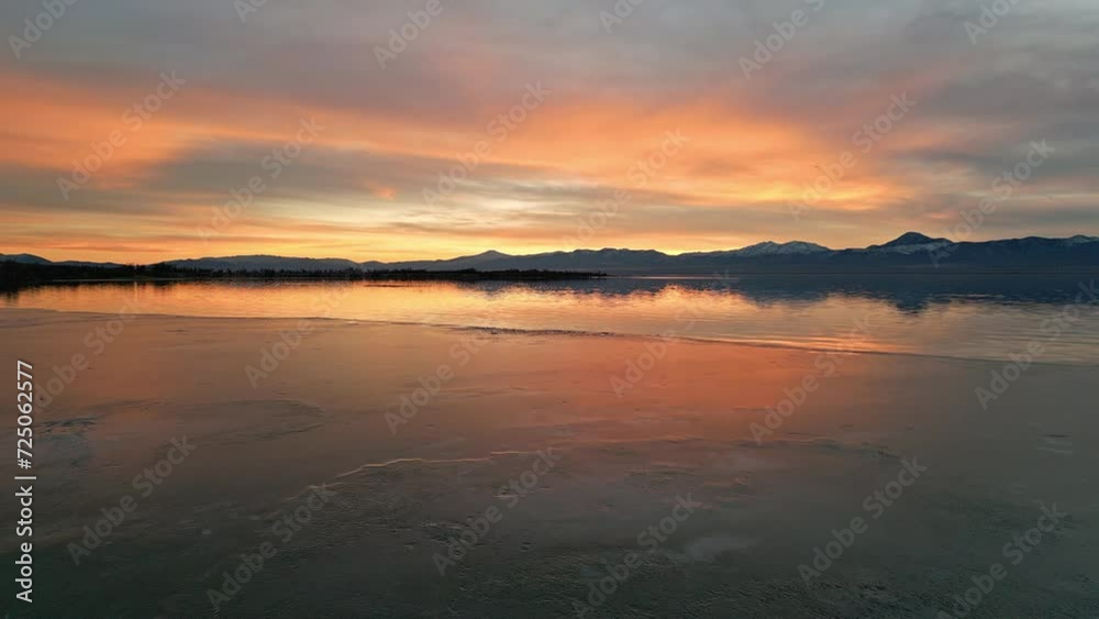Flying over ice on Utah lake during colorful sunset reflecting in the water during winter. Flying over ice on Utah lake during colorful sunset reflecting in the water during winter.