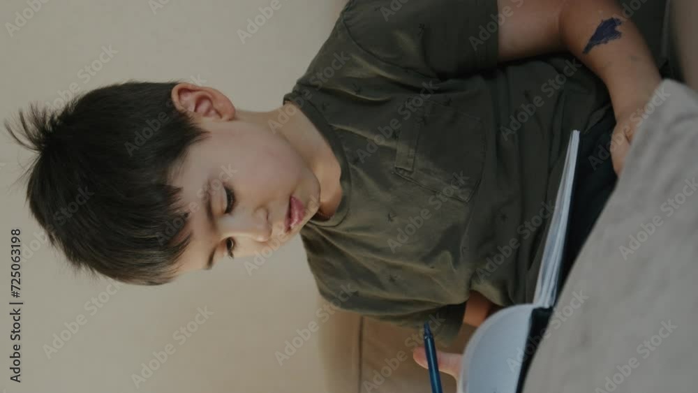 Preteen boy reading relaxing on sofa ddoing homework in living room at home. School student, tired. Dedicated child. Preteen boy reading relaxing on sofa ddoing homework in living room at home. School student, tired. Dedicated child.