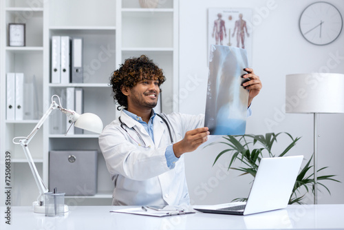 Smiling young male physician reviewing a patient's X-ray in a well-lit, modern medical office, showcasing expertise and care.