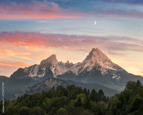 A majestic mountain formation, the Watzmann in Bavaria, Germany, with a colorful sunset sky and woodlands in the foreground © Smileus