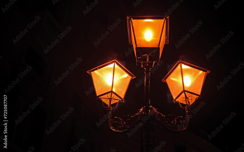 Three illuminated antique street lamps with black background in Genoa, Italy Three illuminated antique street lamps with black background in Genoa, Italy