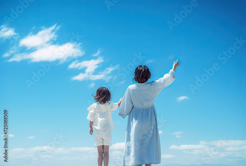 close up photo of mother and daughter. blue sky with white clouds. 