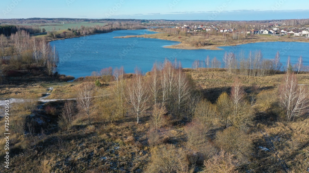 A huge blue lake. Nature and landscape of Europe in winter, cold late fall. Human settlement of village type near antique dark blue lake. Clean air, good ecology of country life.