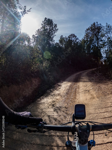 Riding amountain bike with wide handlebar and gps computer on a sandy forest path rider point of view photo