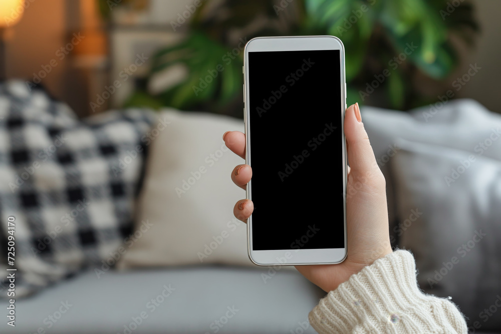 A woman holding a futuristic smartphone with a black screen in a room. Best for mobile application development mockups and background