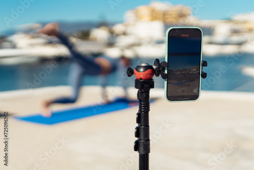 A woman films herself on a mobile phone and broadcasts her workout on social networks. Record your workout on your phone. fitness trainer records your workout online