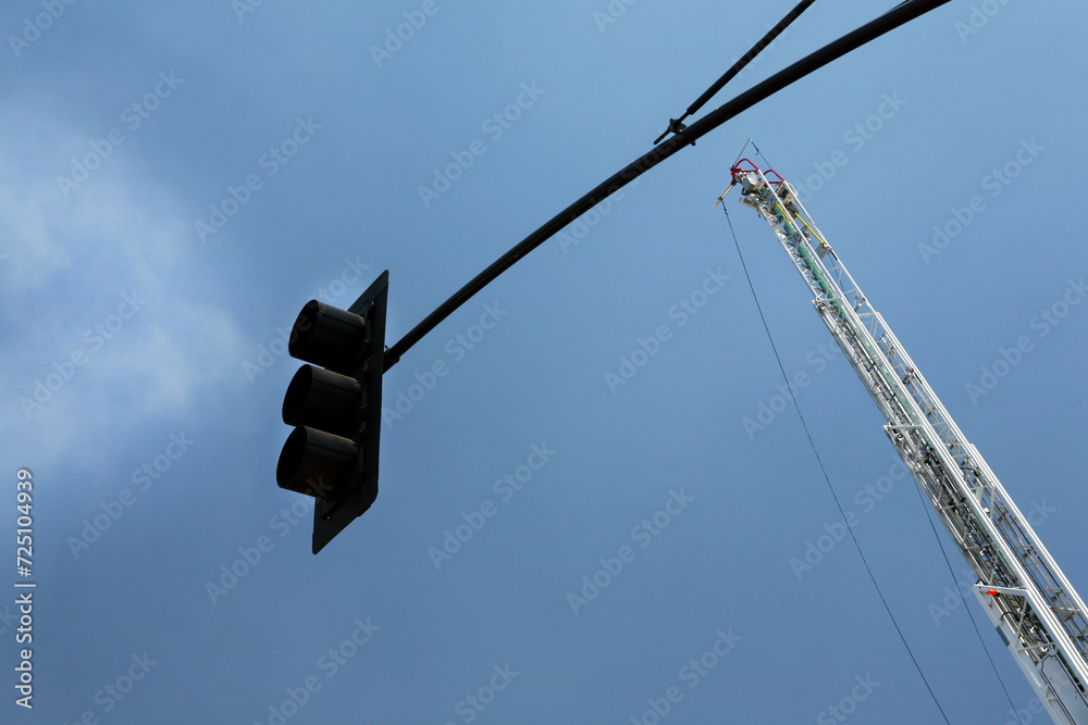 Horizontal image of an unmanned water canon on a hook and ladder fire engine with a traffic stoplight in the foreground and a blue sky background. Horizontal image of an unmanned water canon on a hook and ladder fire engine with a traffic stoplight in the foreground and a blue sky background.